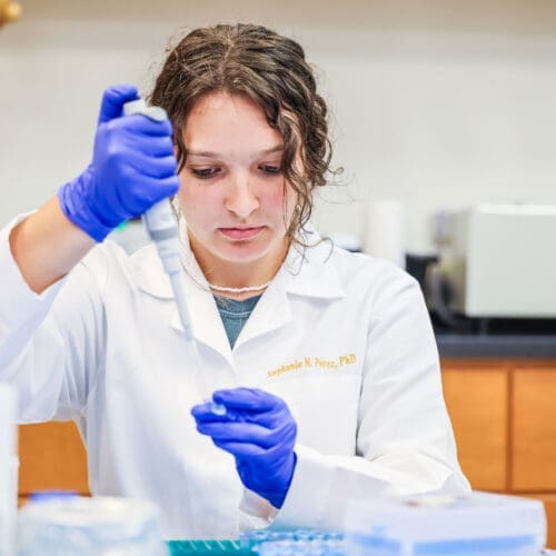 A TLU Student Working in the lab with test tubes.