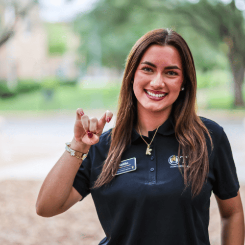 Girl with brown hair doing the "pups up" hand sign