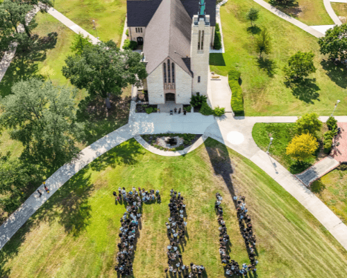 Drone shot of students spelling out TLU in front of chapel