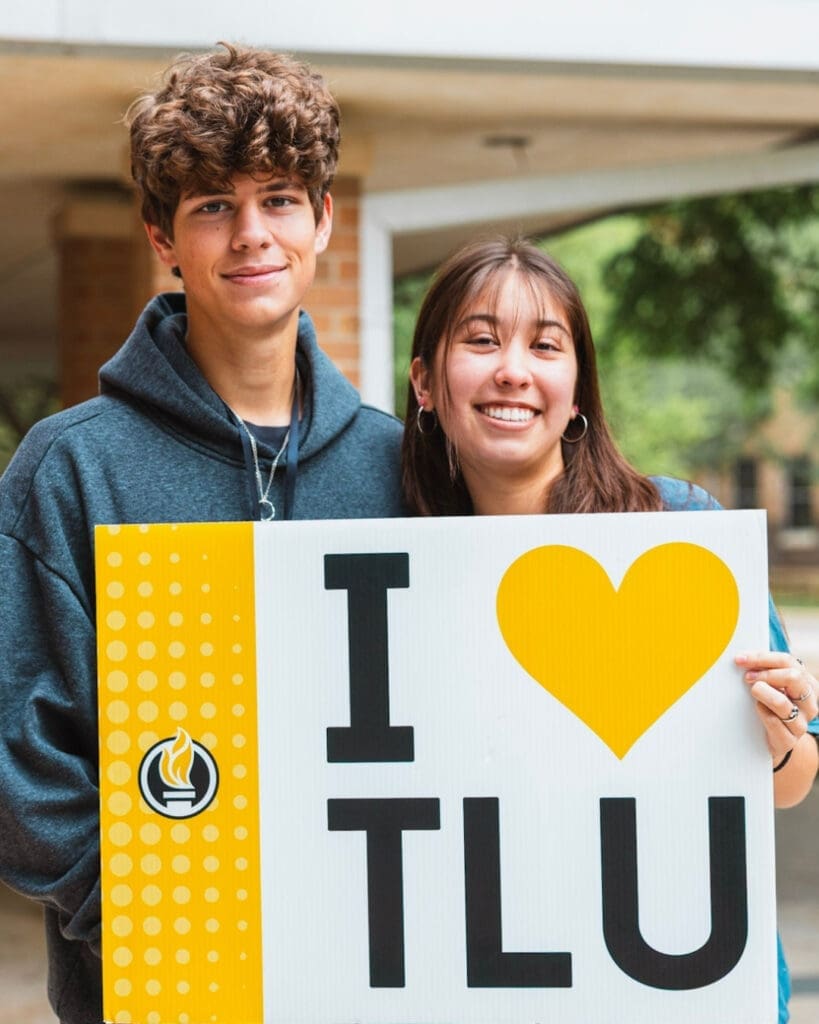 Two students, a male and a female, holding an "I love TLU" sign