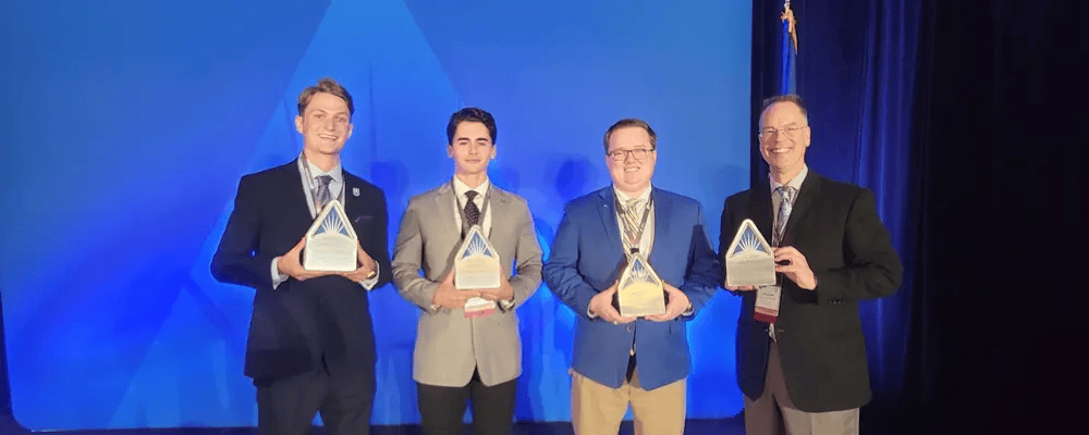 A group of students and professors hold awards they received.