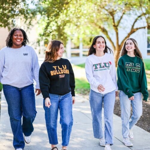 four students walking on sidewalk