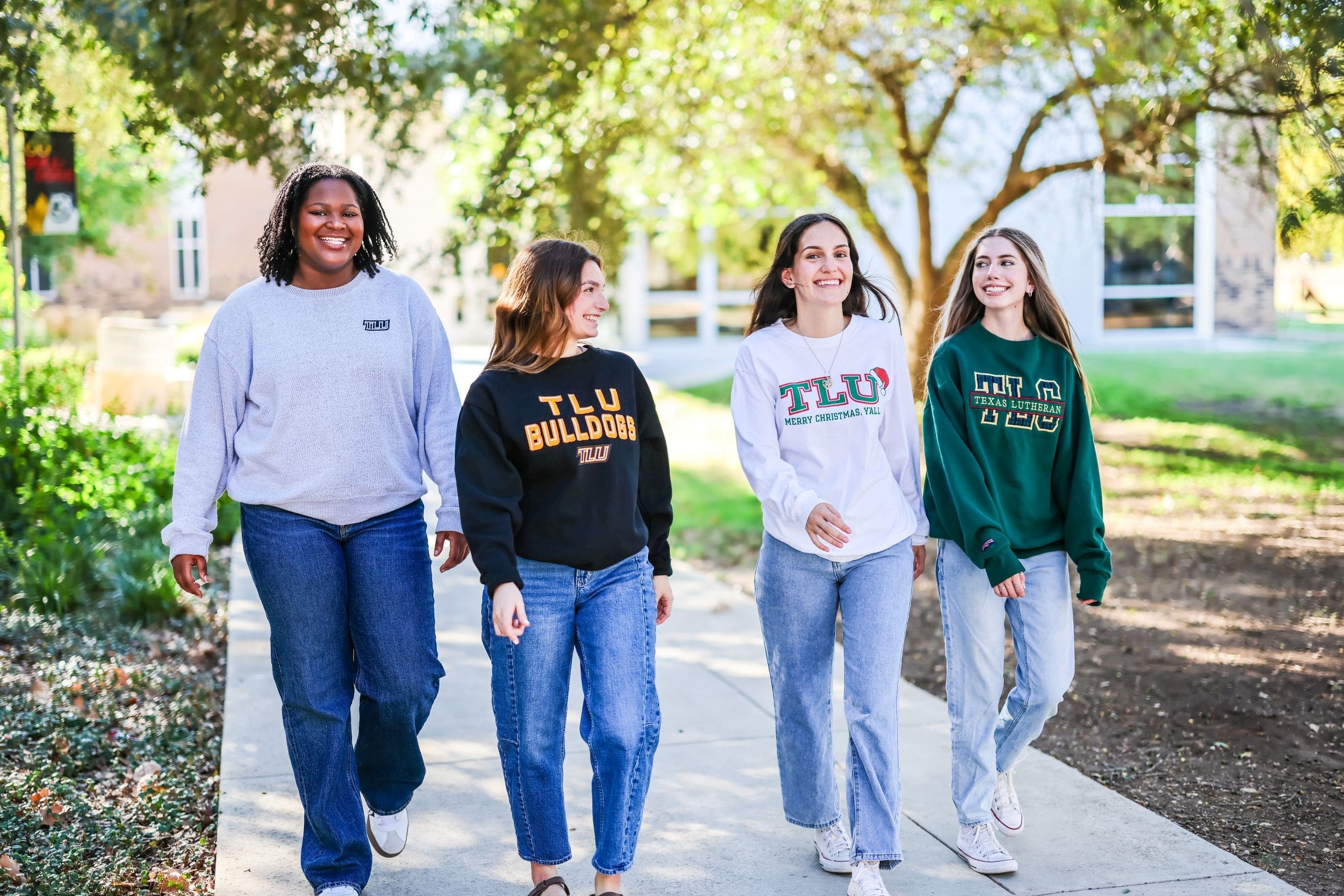 four students walking on sidewalk