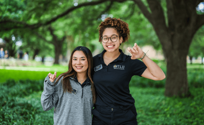 two students holding up TLU Pups UP