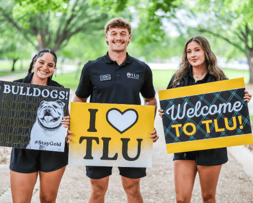 3 students with welcoming signs