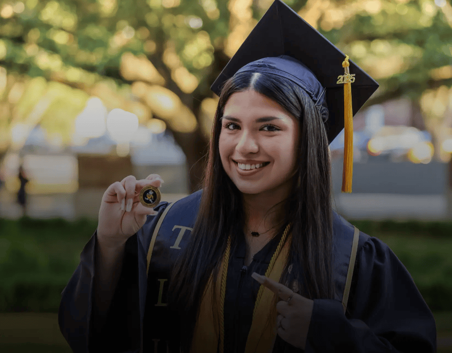 Graduate holding alumni coin