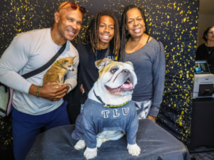 A mom, dad, their dog, and their son posing for a photo with Talulah the Bulldog