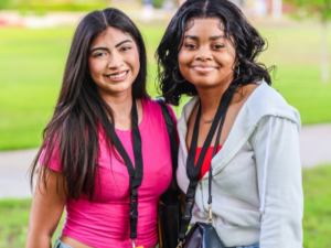 Two girls smiling for a photo in a pink shirt and a gray jacket